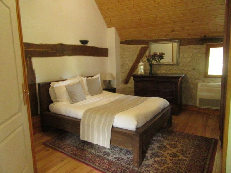 Chambre avec poutres et mur en pierre